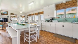 A modern kitchen with white cabinetry, a wooden dining table, and a bench. - Home on Caney Creek with Pier & RV spot (Sargent)
