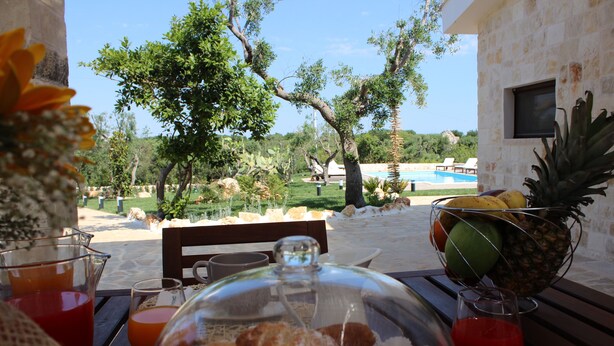A table with breakfast items, a fruit bowl, and a view of a pool and trees. - MONOPOLI: "MEST PEPP "VILLA with POOL FOR EXCLUSIVE GUESTS' USE- MOSQUITOES FREE (MONOPOLI(BA))