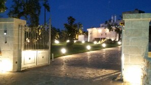 Une entrée fermée par un portail, avec un chemin de pierre menant à un bâtiment.