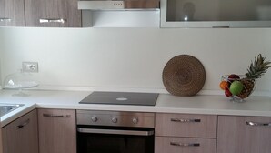 A modern kitchen with a built-in oven, a stove, and a sink. There is a fruit bowl on the counter and a decorative plant on the wall. - MONOPOLI: "MEST PEPP "VILLA with POOL FOR EXCLUSIVE GUESTS' USE- MOSQUITOES FREE (MONOPOLI(BA))