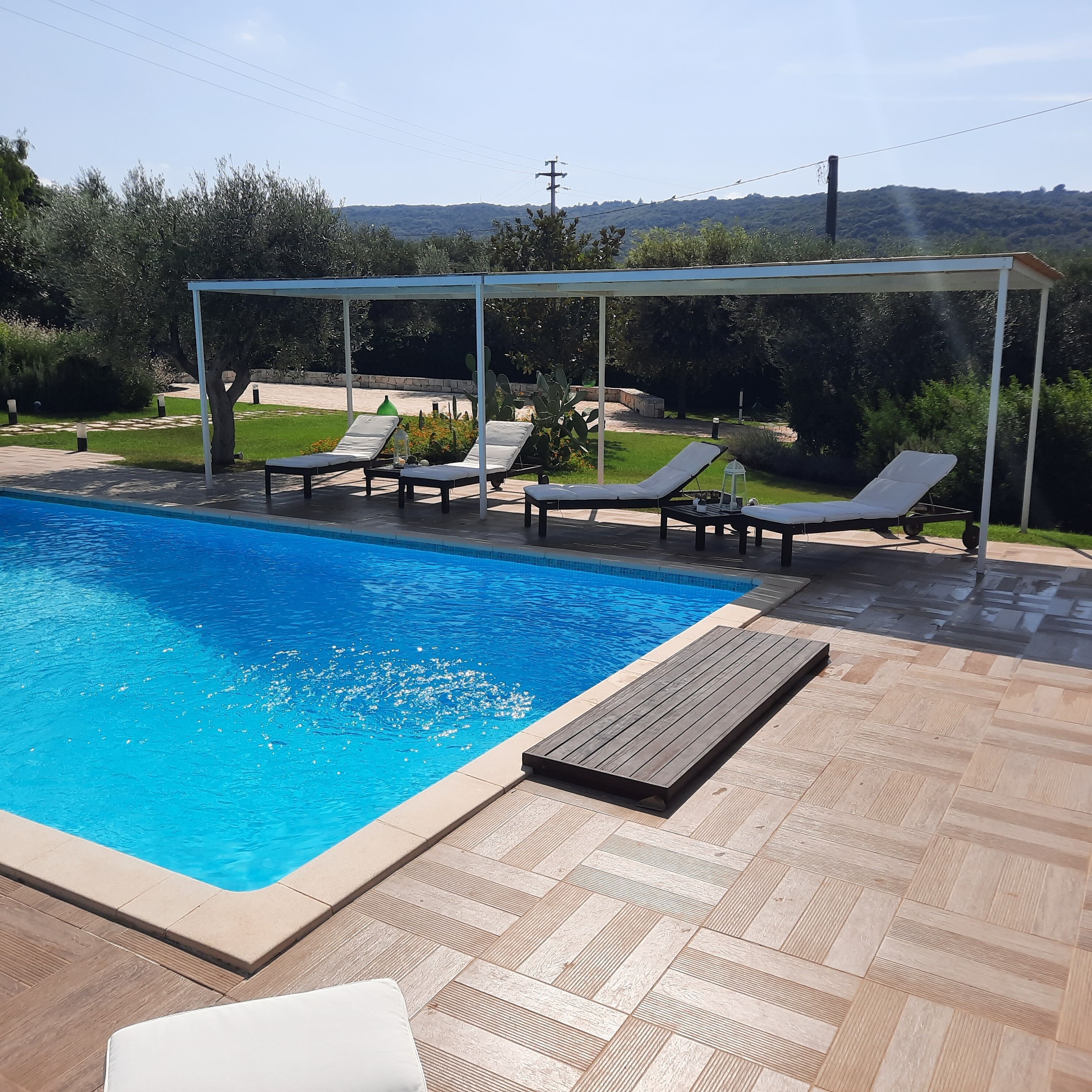 A swimming pool with lounge chairs and a pergola.