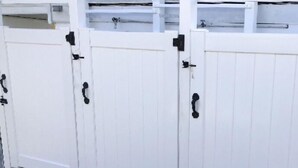 A white metal gate with black hinges and a latch.
