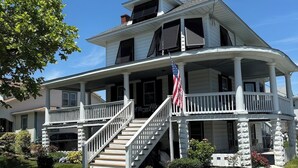A two-story house with a porch, a staircase, and an American flag.