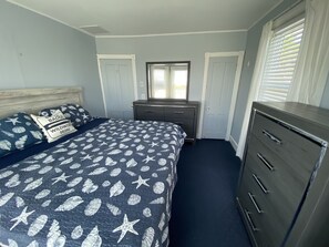 Une chambre à coucher avec un lit, une commode et une fenêtre équipée de stores.