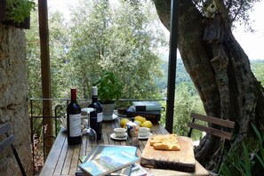Une table en bois, dressée avec une bouteille de vin, des verres, des citrons, un livre et une planche à découper sur laquelle se trouve du pain.
