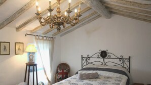 Una camera da letto con un letto, un lampadario, una lampada, una sedia e una bandiera britannica.