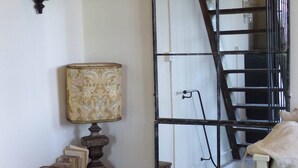 Una stanza con un tavolo di legno, una lampada, uno specchio e una scala.