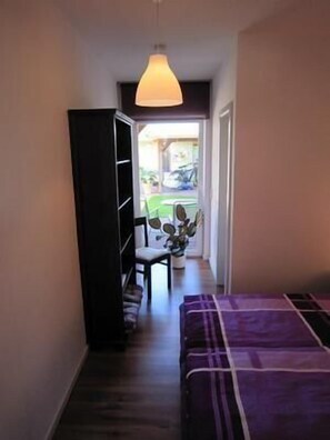 Cozy retreat with a single bed, seating area, and wardrobe, offering a view of the outdoor space.