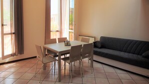 A dining area with a table and chairs, a sofa, and large windows with curtains. - Large duplex apartment sleeps 5, private parking space, in the center  (Ravenna)