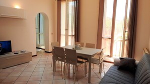 A dining area with a table and chairs, a sofa, and a television on a stand. - Large duplex apartment sleeps 5, private parking space, in the center  (Ravenna)