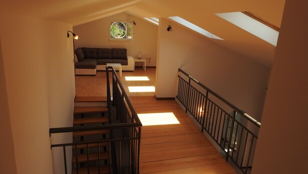 A staircase with wooden steps and a black railing, leading to a living area with a sofa and a small table. - Large duplex apartment sleeps 5, private parking space, in the center  (Ravenna)