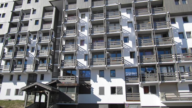 A multi-story residential building with balconies, a stone entrance, and a small covered area. - Exeptional luxury duplex of 85 m² in Val Thorens for 8 people (Les Belleville)