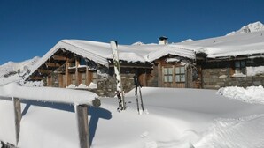 A stone chalet with wooden beams and a snow-covered roof, surrounded by snow. - Exeptional luxury duplex of 85 m² in Val Thorens for 8 people (Les Belleville)