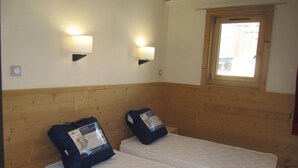 A room with two single beds, wooden headboard, two wall-mounted lamps, a window, and a small wooden nightstand. - Exeptional luxury duplex of 85 m² in Val Thorens for 8 people (Les Belleville)