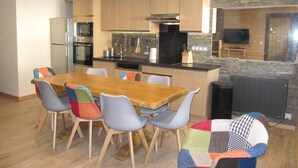 A modern kitchen with wooden cabinets, a dining table with colorful chairs, and a built-in oven. - Exeptional luxury duplex of 85 m² in Val Thorens for 8 people (Les Belleville)