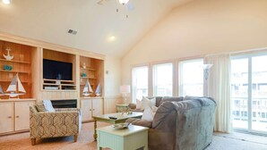 A living room with a sofa, a patterned armchair, a small table, and a TV on a wooden cabinet. - 6 bedrooms, elevator,  3 minute walk to the beach. (Kill Devil Hills)