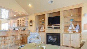 A living room with a fireplace, wooden shelves, and a television. - 6 bedrooms, elevator,  3 minute walk to the beach. (Kill Devil Hills)