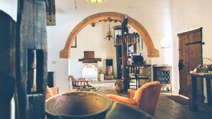 A rustic room with a large arched doorway, wooden furniture, and a hanging light fixture.