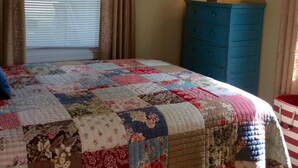 A bedroom with a large bed, a dresser, a lamp, and a window with curtains. - ☀️Summer dates available!  (Mears)