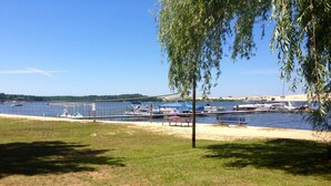 A lakeside view with boats docked, a picnic table, and a tree in the foreground. - ☀️Summer dates available!  (Mears)