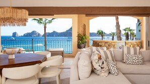 A modern living room with a view of the sea, a wooden table, and a sofa with patterned cushions. - Luxury Oceanfront Villa - Endless Panoramic Ocean and Pool Views! (Cabo San Lucas)