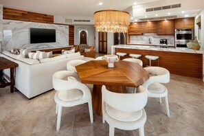 A modern kitchen with wooden cabinets, a built-in oven, and a large island with stools. - Luxury Oceanfront Villa - Endless Panoramic Ocean and Pool Views! (Cabo San Lucas)