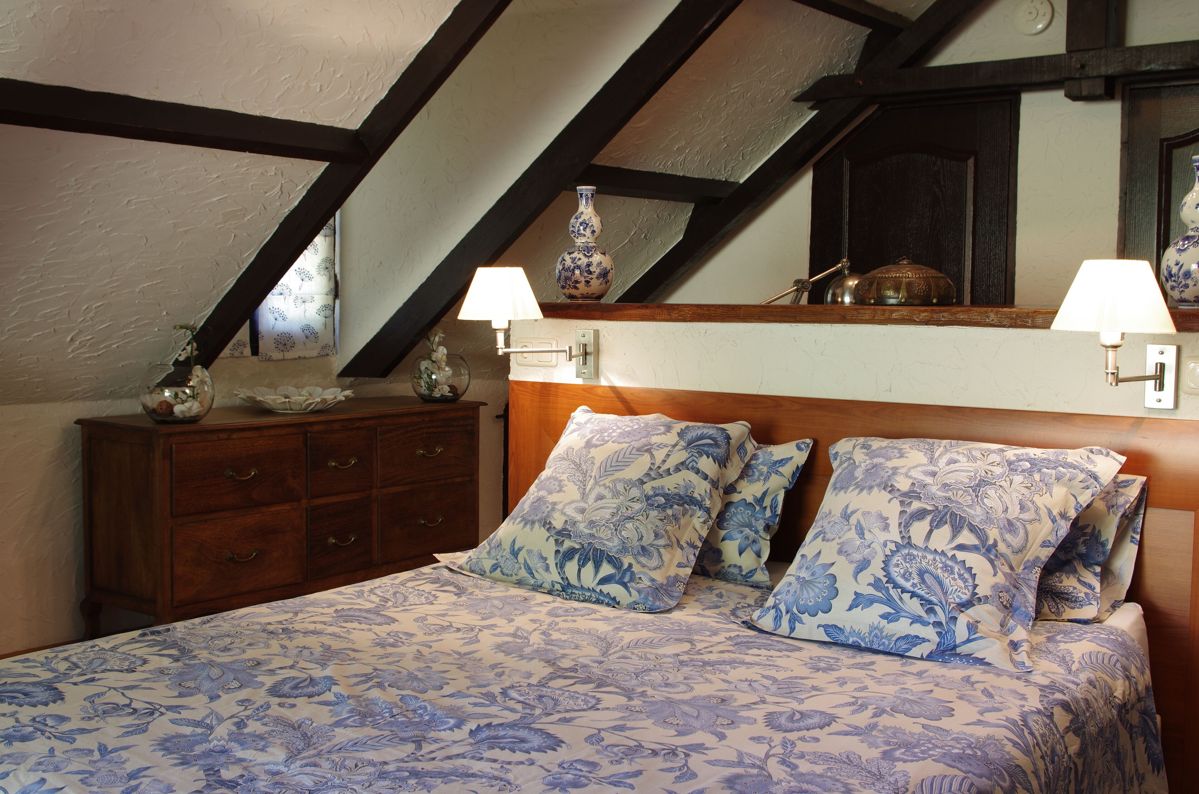 A bedroom with a bed, two nightstands, a dresser, and a mirror.
