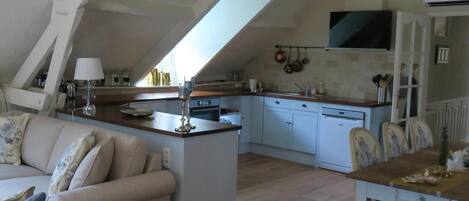 An attic-style living space with a kitchen, wooden flooring, and a dining area.