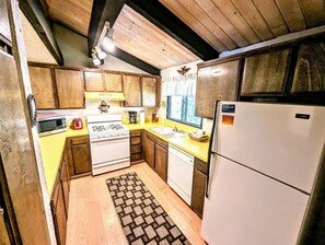 A kitchen with wooden cabinets, a stove, a microwave, and a refrigerator. - Charming Forest Retreat – Steps from Snow Summit Slopes (BIG BEAR LAKE)