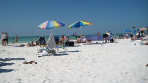 Une plage avec de nombreux parasols colorés, des chaises longues et des gens qui se détendent.