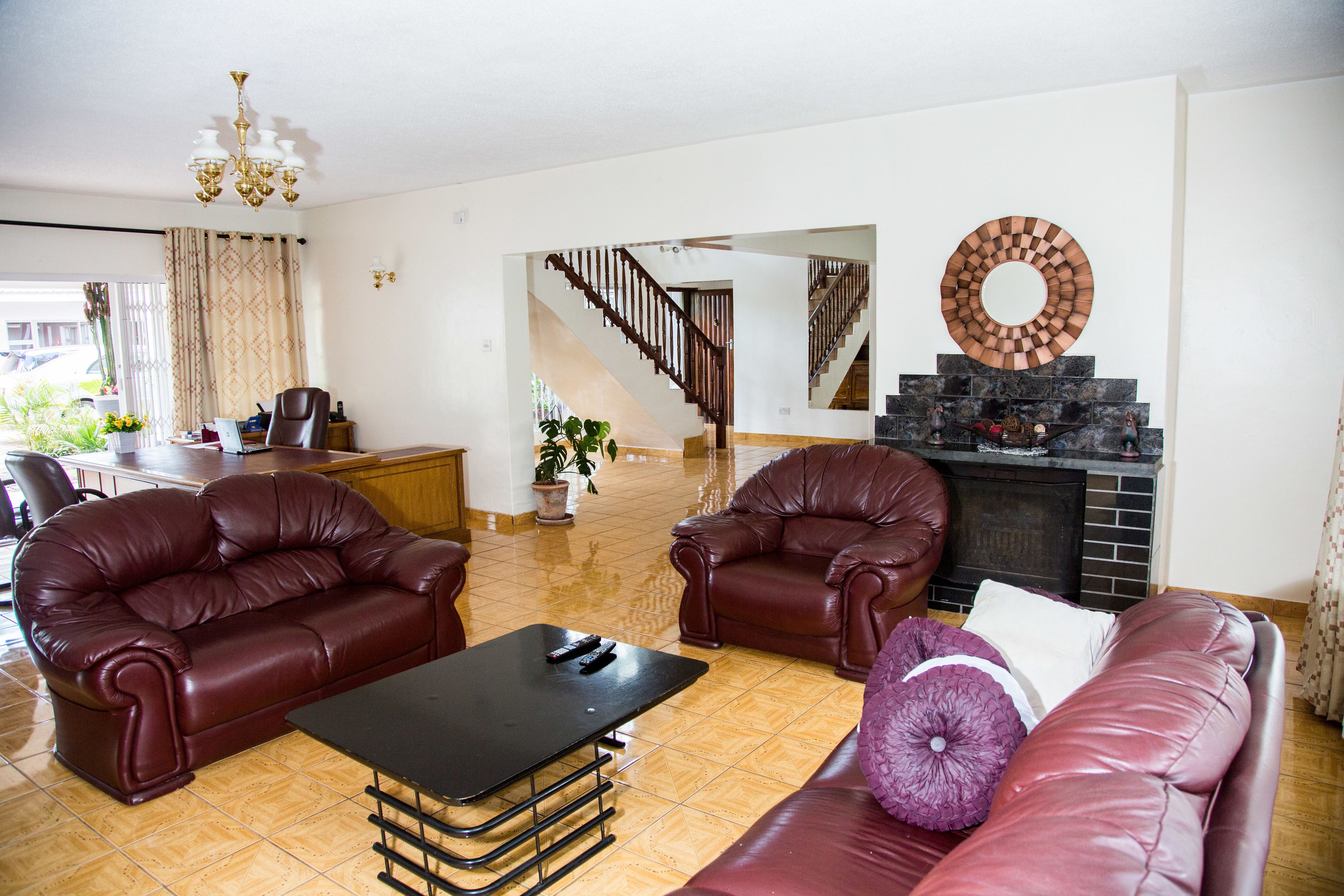 A living room with a fireplace, leather sofas, and a dining area with a table and chairs.