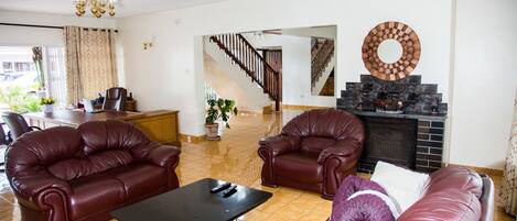A living room with a fireplace, leather sofas, and a dining area with a table and chairs.