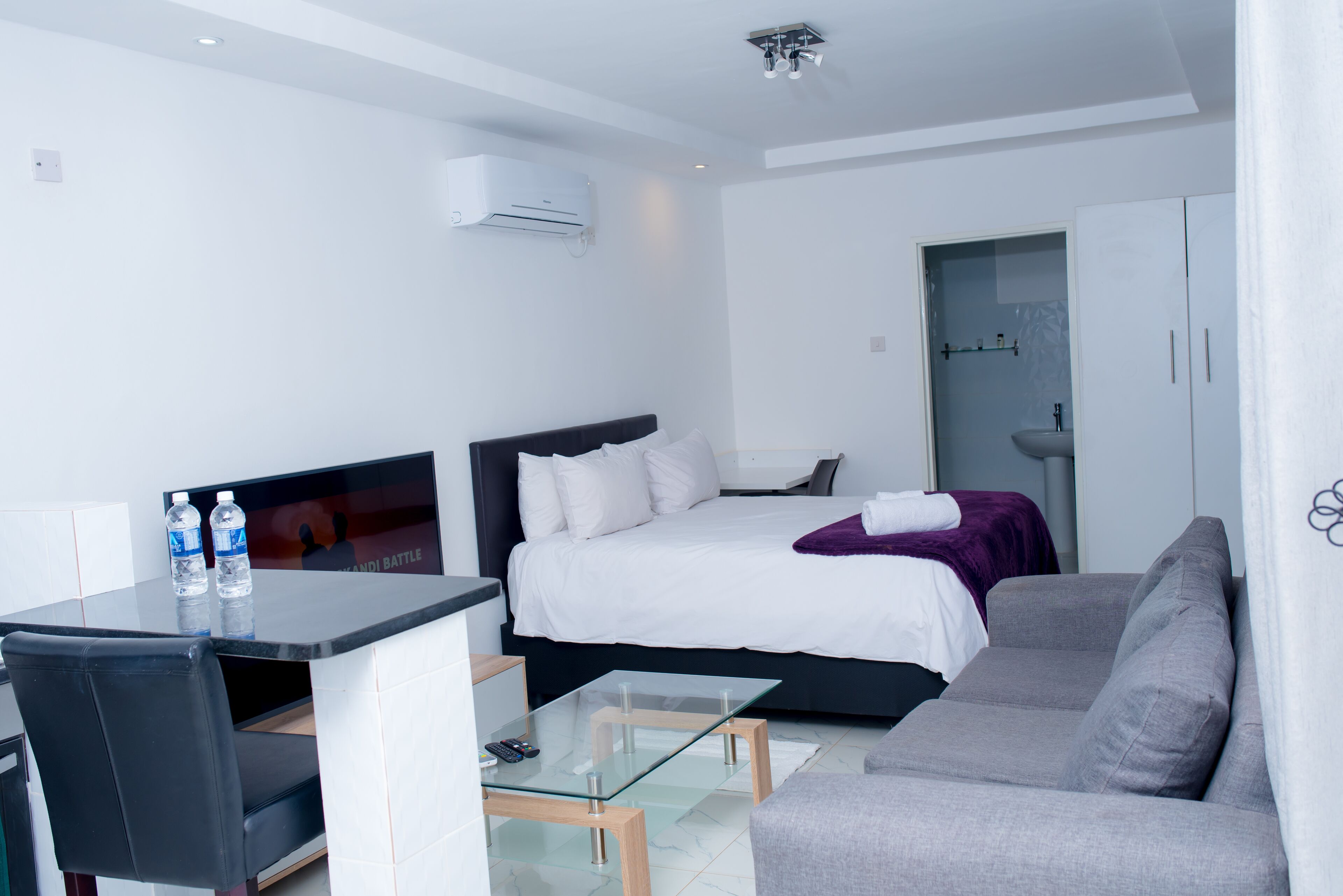 Une chambre d’hôtel moderne équipée d’un lit, d’un canapé, d’une table en verre et d’un téléviseur.