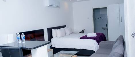 Una habitación de hotel moderna con una cama, un sofá, una mesa de vidrio y una televisión.