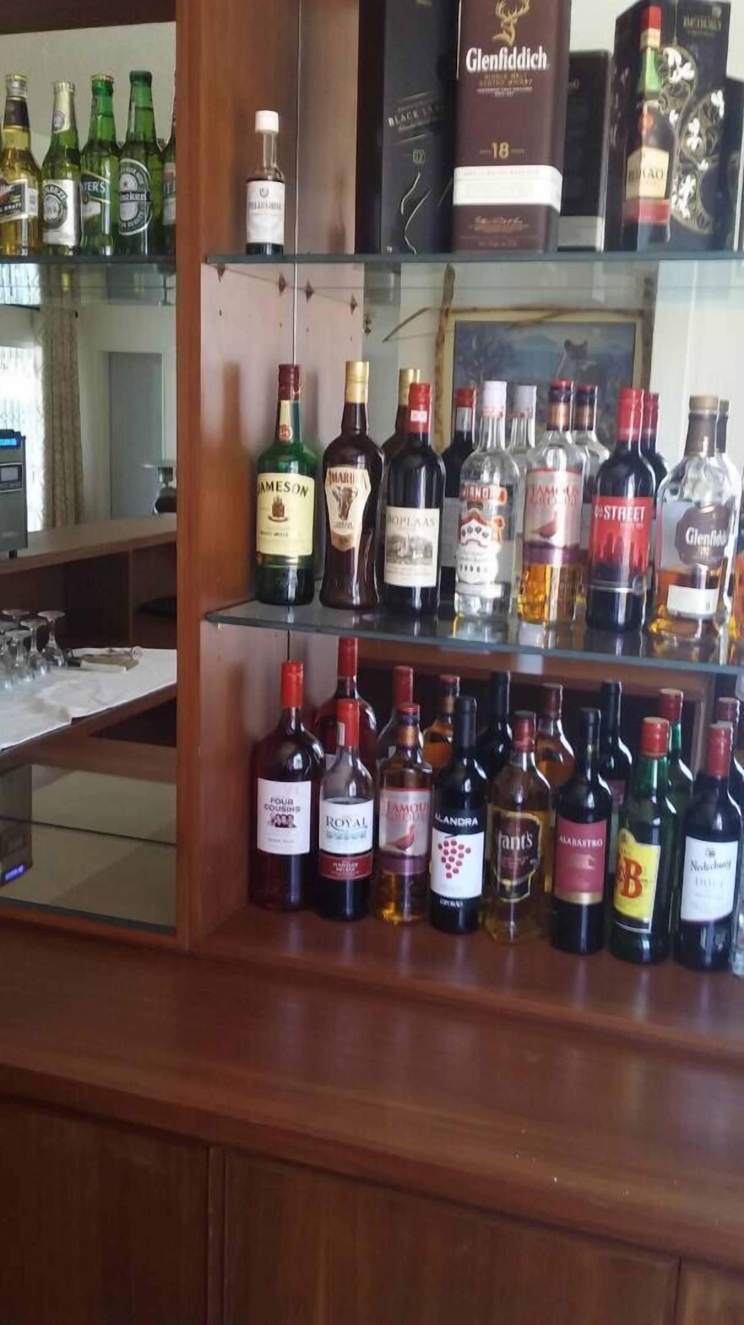 Zona de bar con diversas botellas de alcohol, incluyendo whisky, vino y licores, exhibidas en estantes.