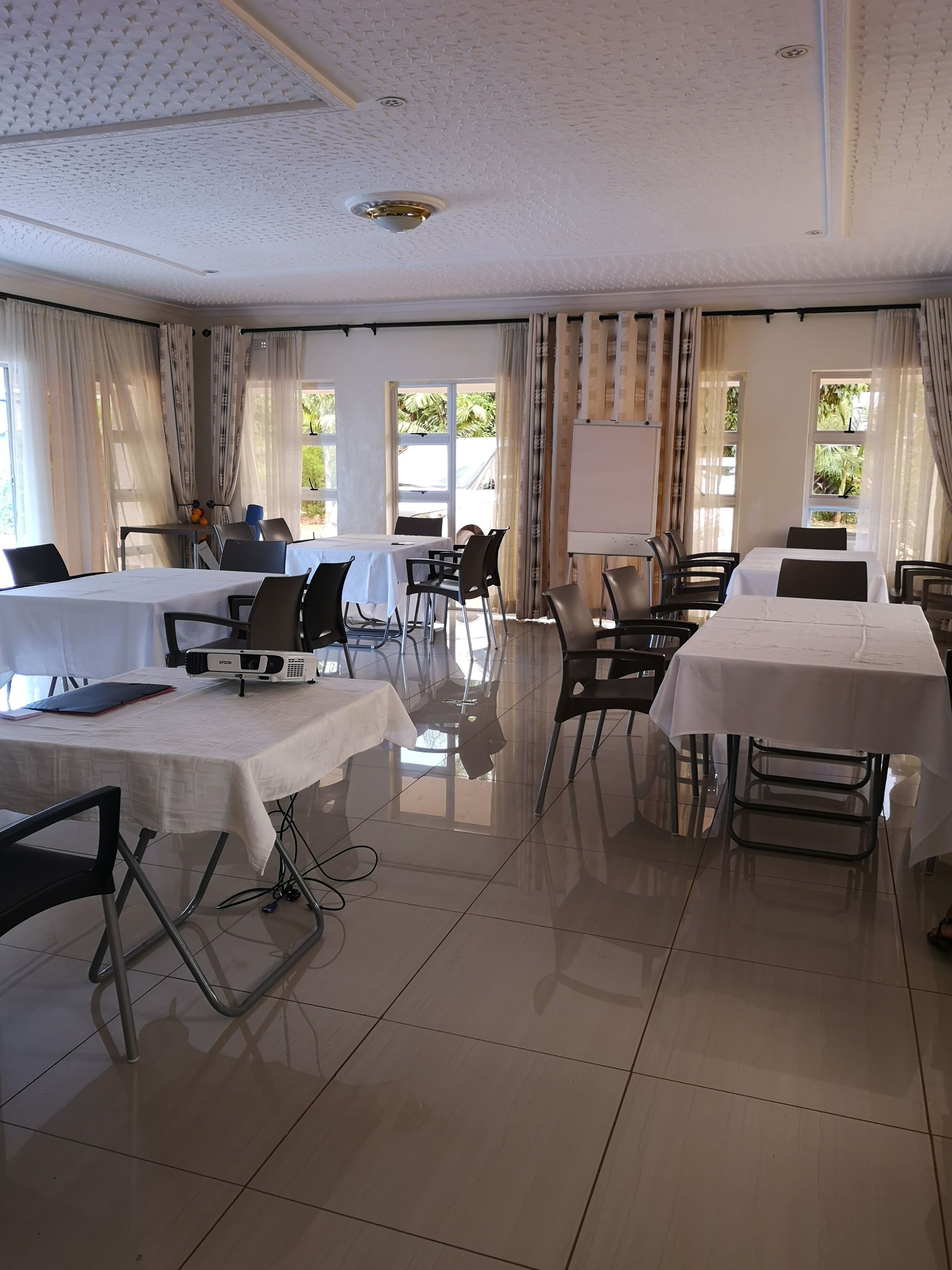 Un salón de conferencias con dos mesas, sillas, un proyector y una pizarra.