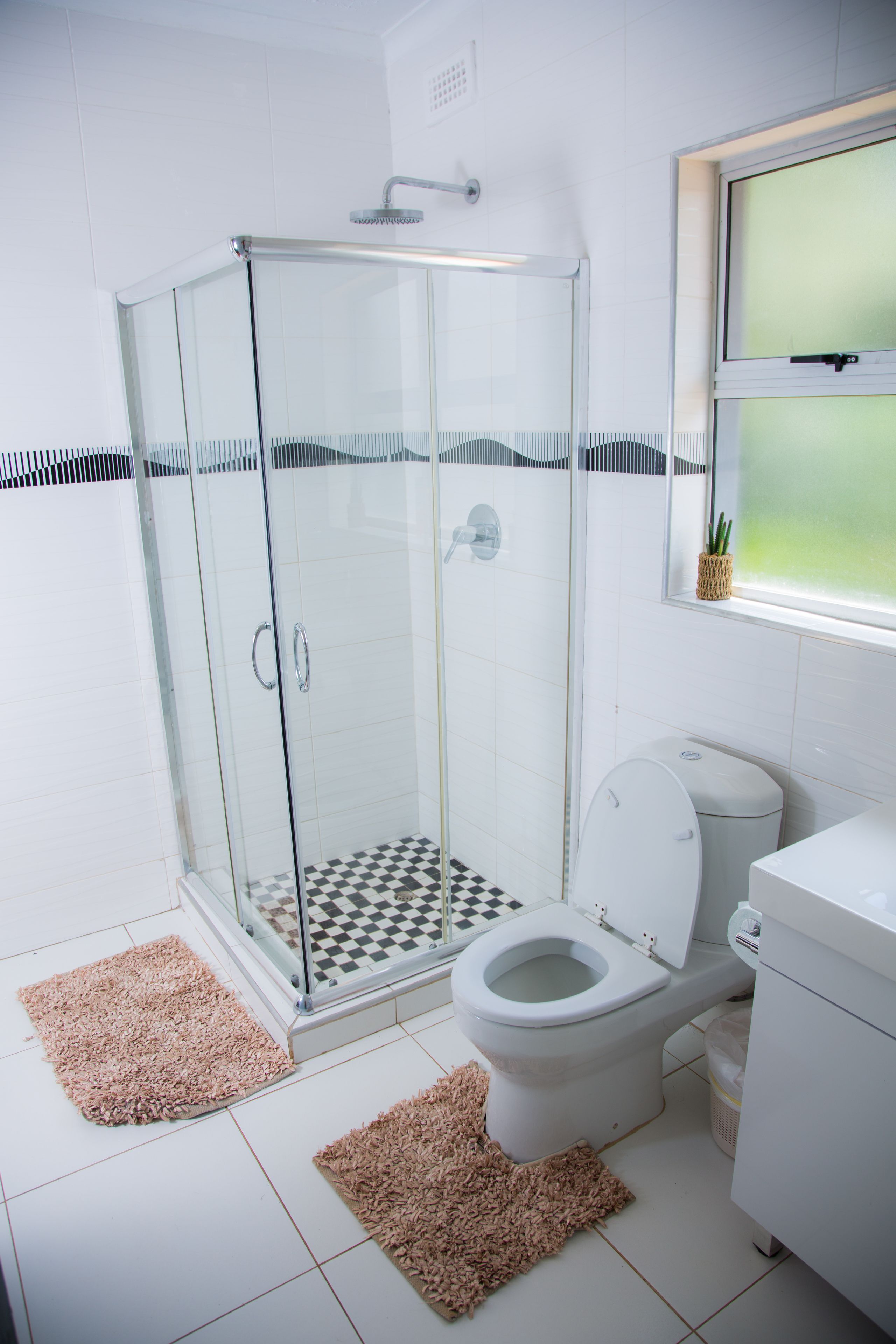 A bathroom with a glass-enclosed shower, a toilet, and a sink.