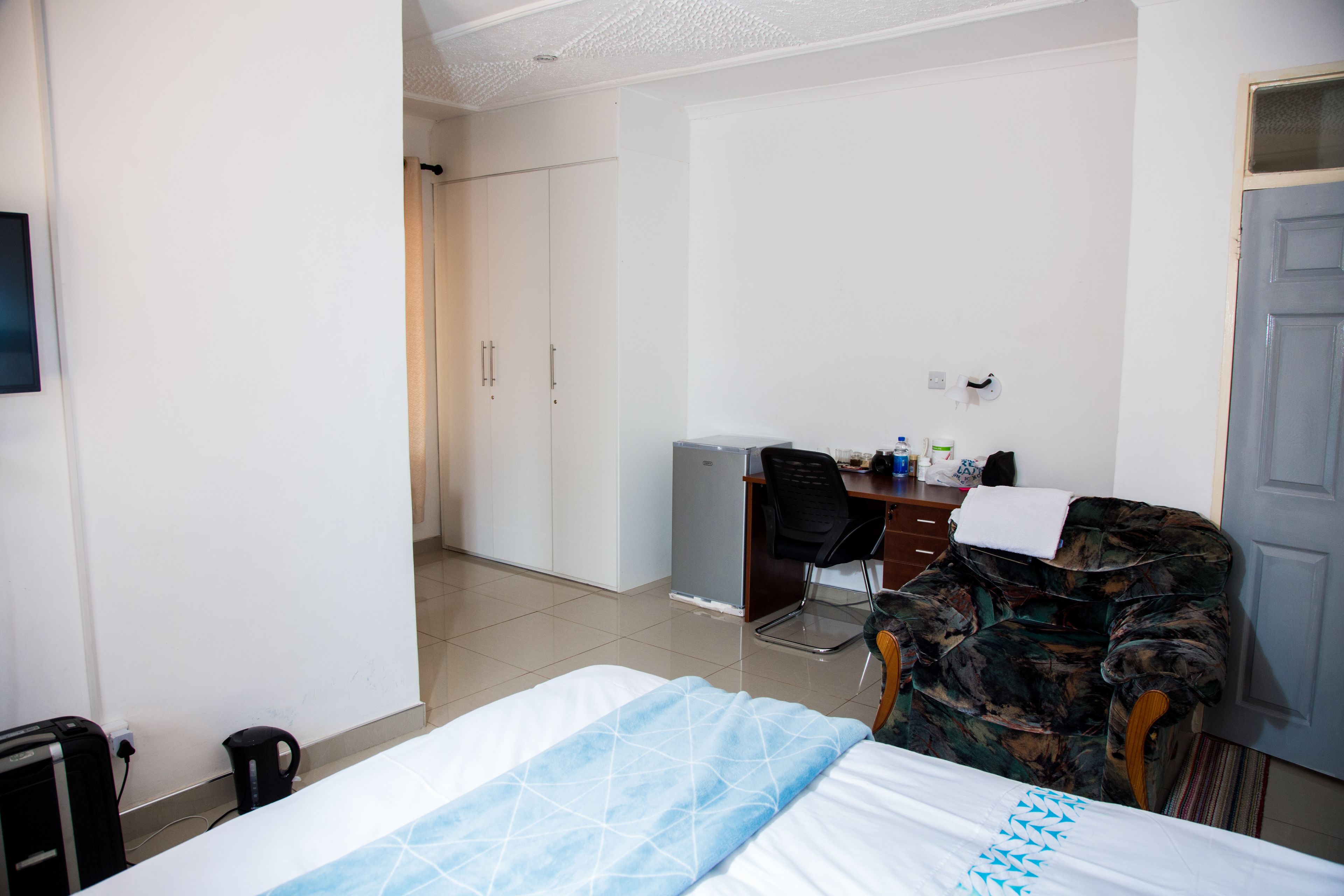 Ein Hotelzimmer mit Bett, Schreibtisch, Stuhl und Kleiderschrank.