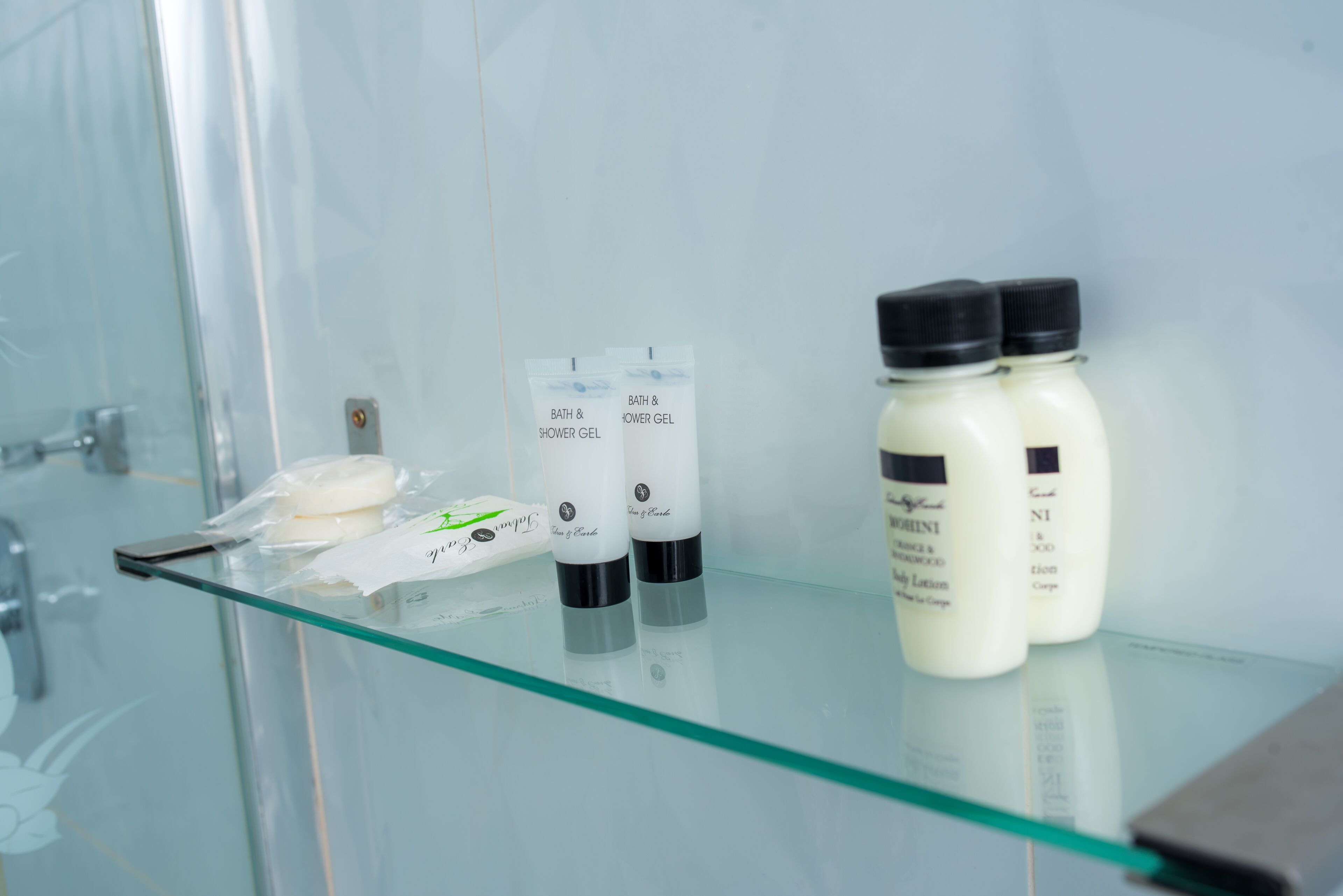 Een badkamerplank met bad- en douchegel, bodylotion en een zeepstaaf.