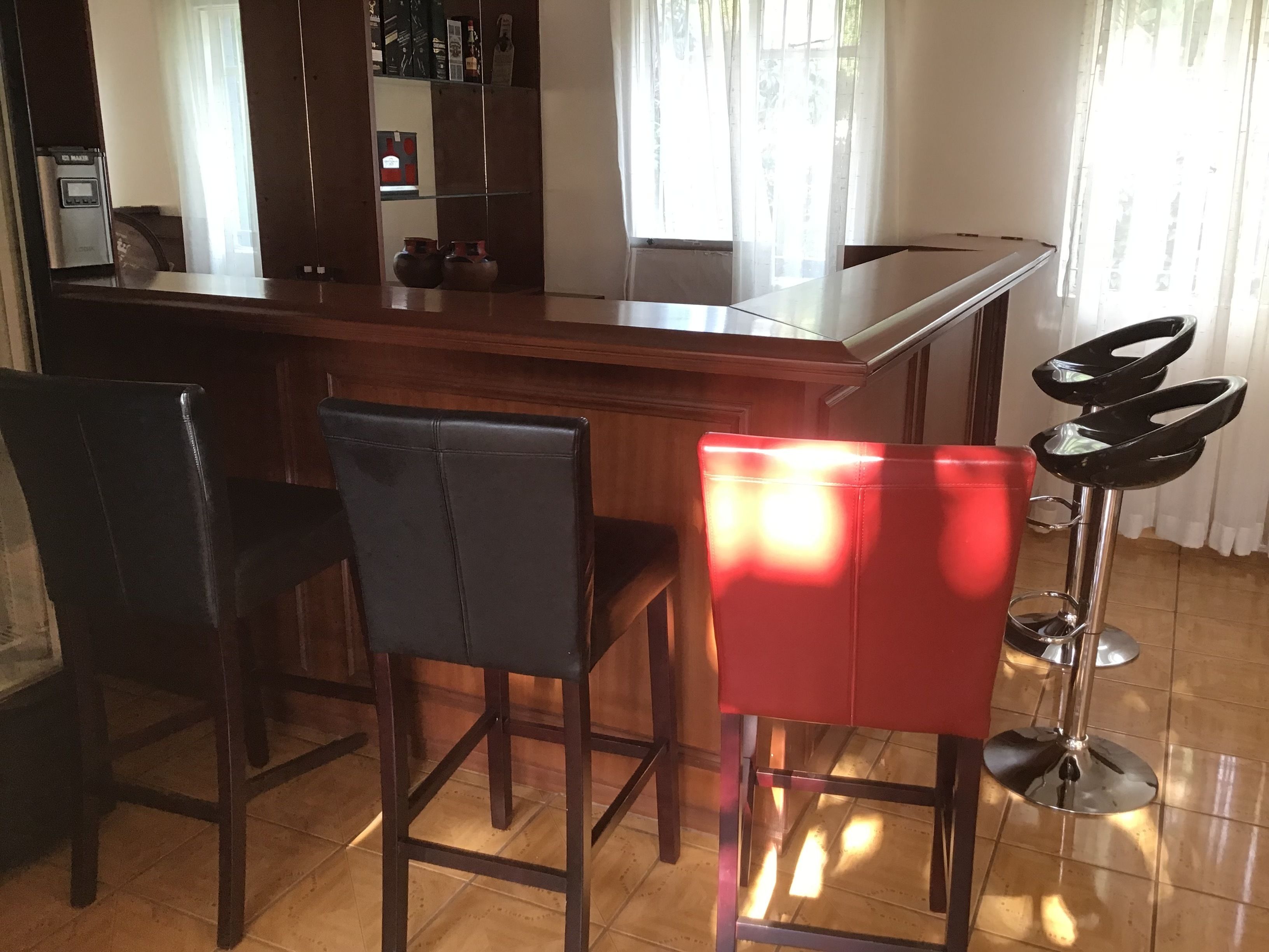 A bar area with a counter, two black chairs, and a red chair.