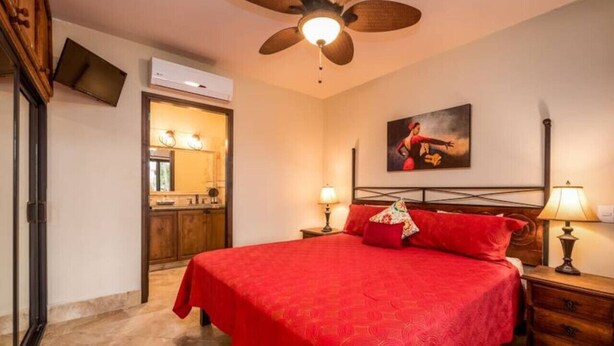 Ein Schlafzimmer mit einem großen Bett, zwei Nachttischlampen, einem Deckenventilator und einem Bild an der Wand.