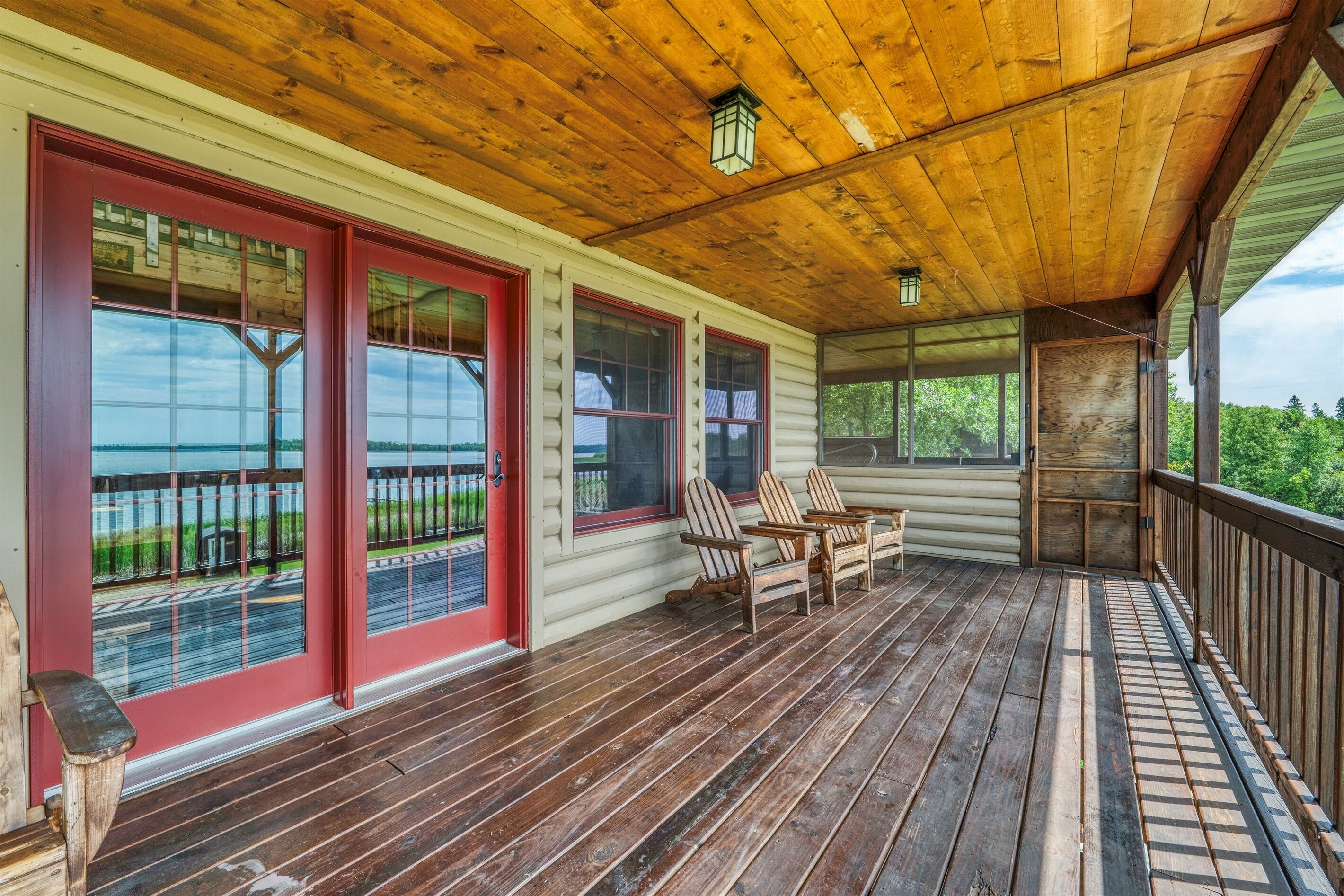 A wooden deck with red-framed windows and a view of the lake.