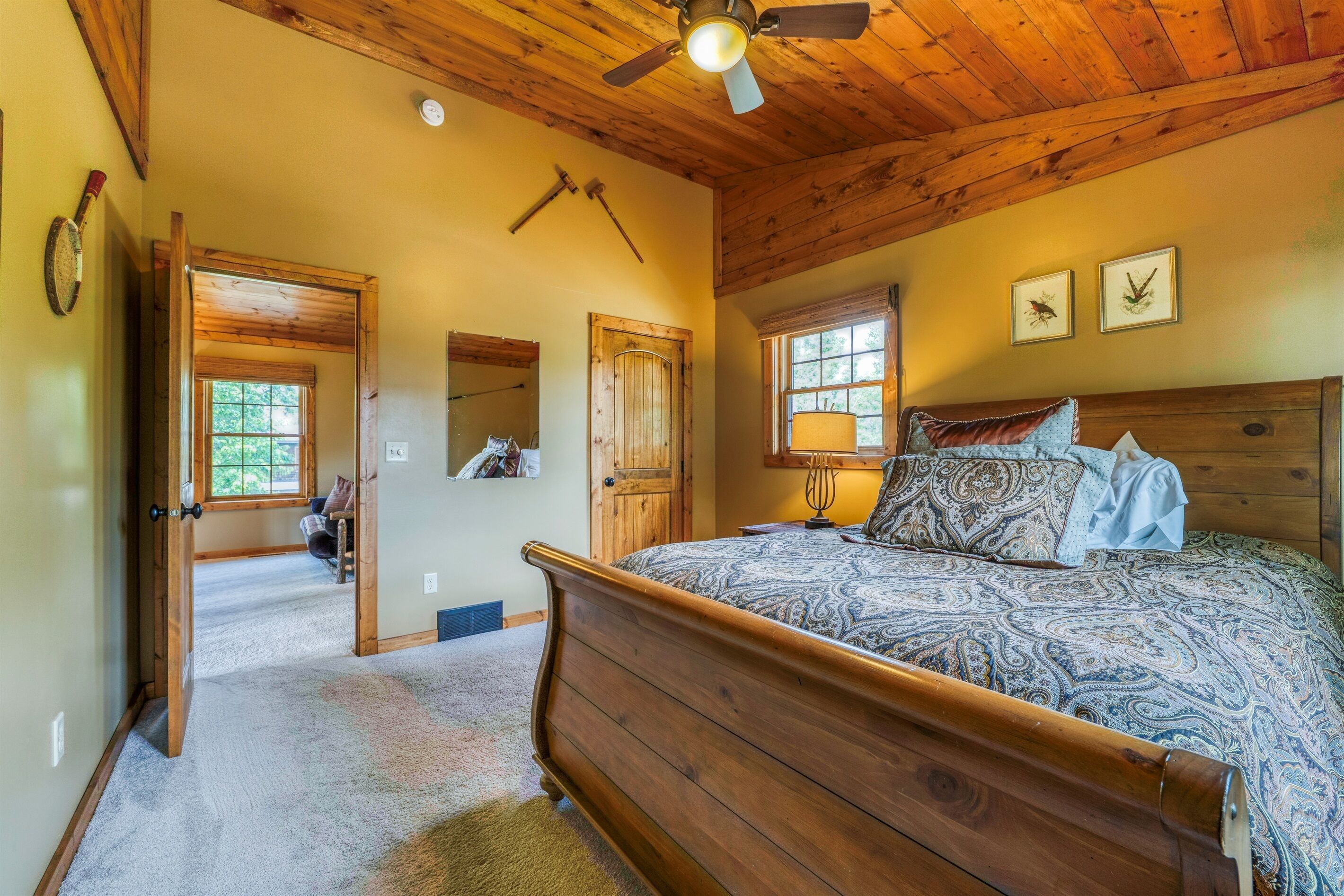 Une chambre à coucher avec un lit en bois, un ventilateur de plafond et une fenêtre donnant sur l’extérieur.