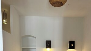 Un dormitorio con cama, una estantería, una lámpara de pared y un jarrón decorativo.