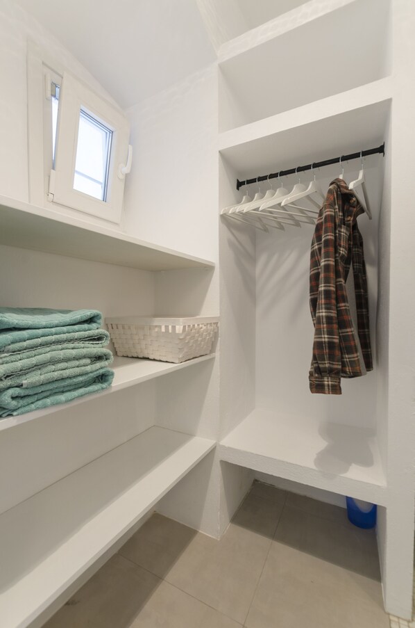 A white closet with shelves, a hanging rack, and a window. - Cosy Quiet Hideaway Loft, perfect location old town Tarifa (Tarifa)