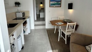 Un espacio habitable compacto con kitchenette, comedor y sofá.
