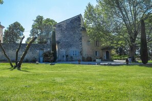 Stands amidst a serene, grassy lawn and mature trees, showcasing its historic, weathered architecture.