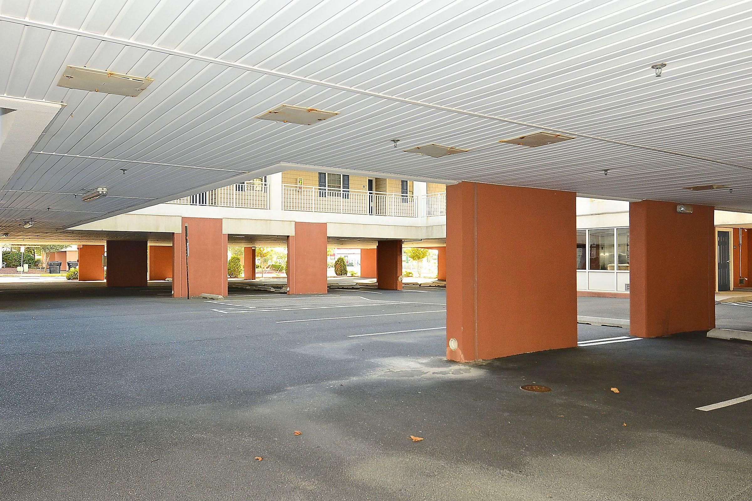 Un parking à plusieurs niveaux, conçu en espace ouvert, avec une série de colonnes et un toit plat.