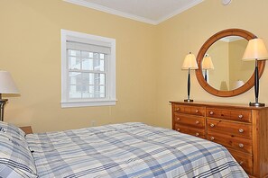 A bedroom with a bed, a dresser, a mirror, and a window.