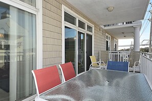 A covered outdoor seating area with a table and chairs, large windows, and a view of the surrounding area.